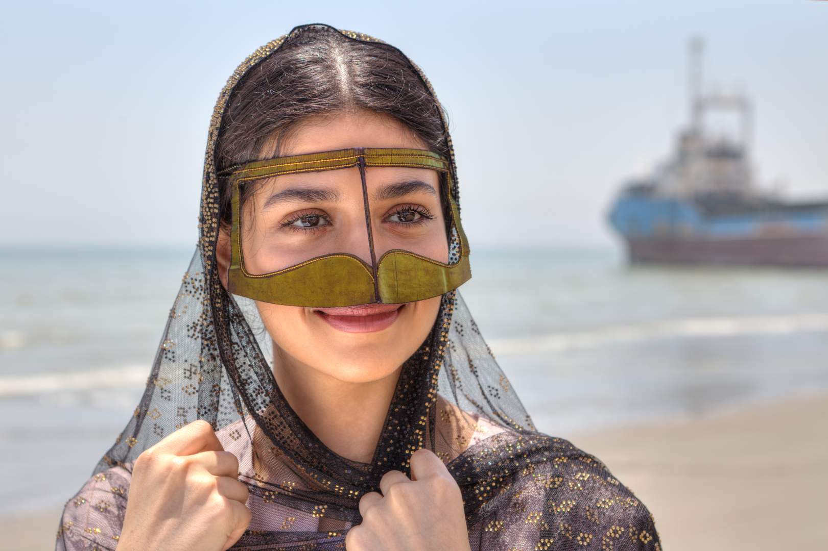 Woman in traditional southern Iranian mask by the Persian Gulf