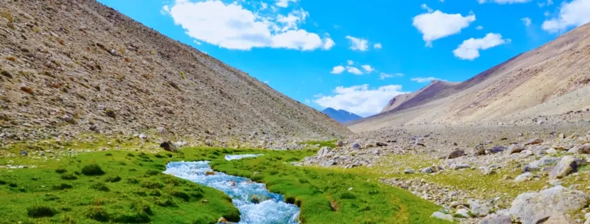 river in between brown mountains under blue sky during daytime